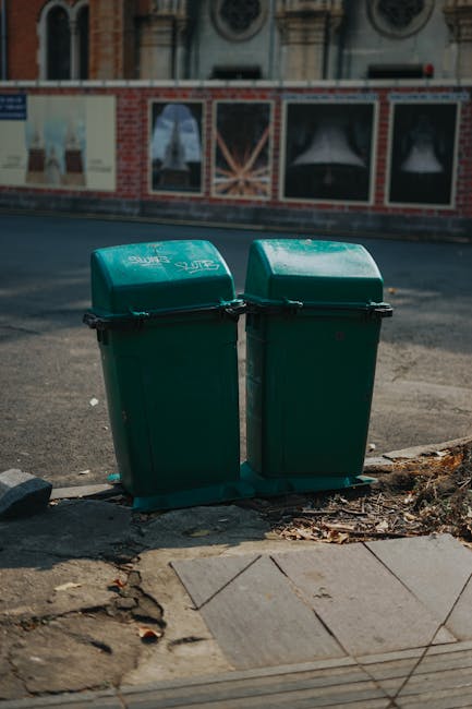A large pile of assorted rubbish is spread across a paved outdoor area, consisting mainly of various discarded materials including paper, plastic bottles, cardboard boxes, and crumpled tissues. The pl